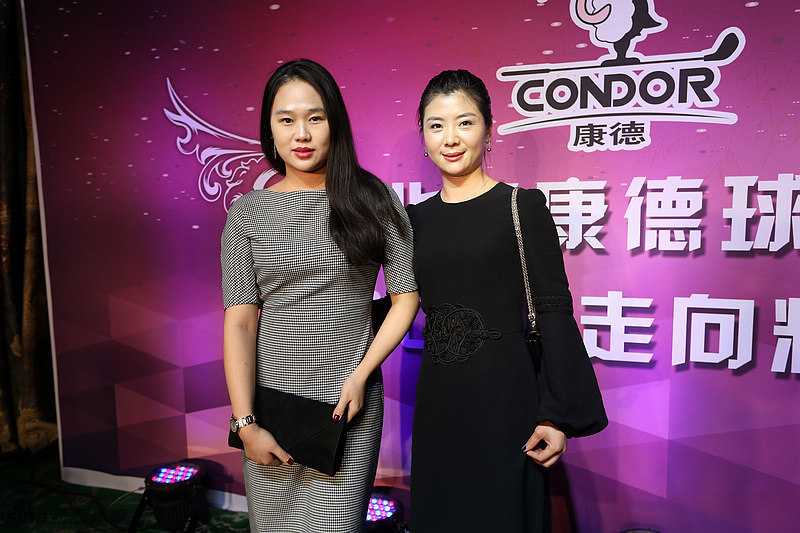 现场抽奖环节气氛热烈，一位幸运儿惊喜地举手示意，背景是大屏幕滚动的号码，周围同事投来羡慕与欢笑的目光