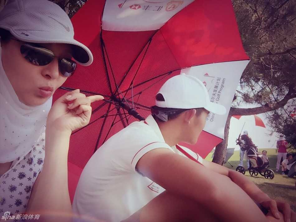 马羚举起手机，为正在调整手套的儿子抓拍特写，她的眼神透过屏幕聚焦在孩子身上，充满了温柔的关注。